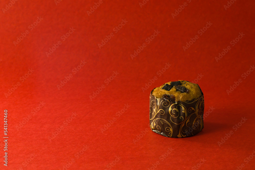 a chocolate chip muffin or cupcake shot against red background with copy space. a chocolate chip muffin or cupcake shot against red background with copy space.