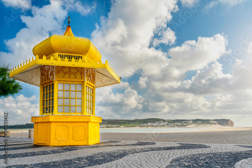 Yellow kiosk on the traditional portuguese paved promenade in front of the Foz do Arelho beach in Caldas da Rainha, Portugal - Travel concept
 photo