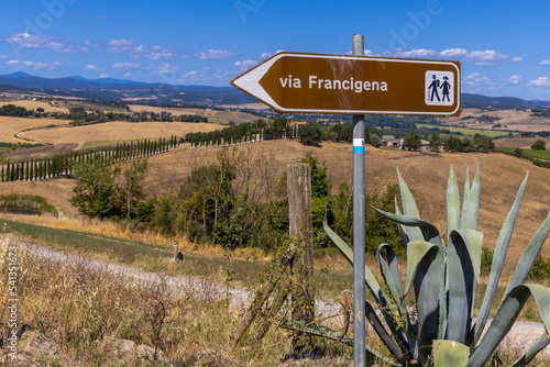 Landscape along via Francigena with Mud road, fields, trees and vineyard.  Sign showing the direction of Monteroni d'Arbia, route of the via francigena. Siena province, Tuscany. Italy, Europe.