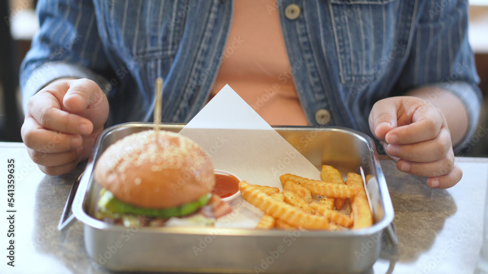 Woman enjoy eating a hamburger and french fries