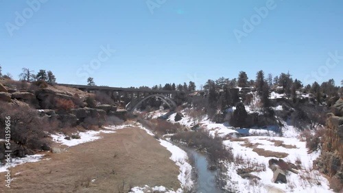 Cinematic Drone Shot Going Under Bridge in Canyon on Snowy Day • Dramatic Aerial Footage • Horizontal HD Video photo