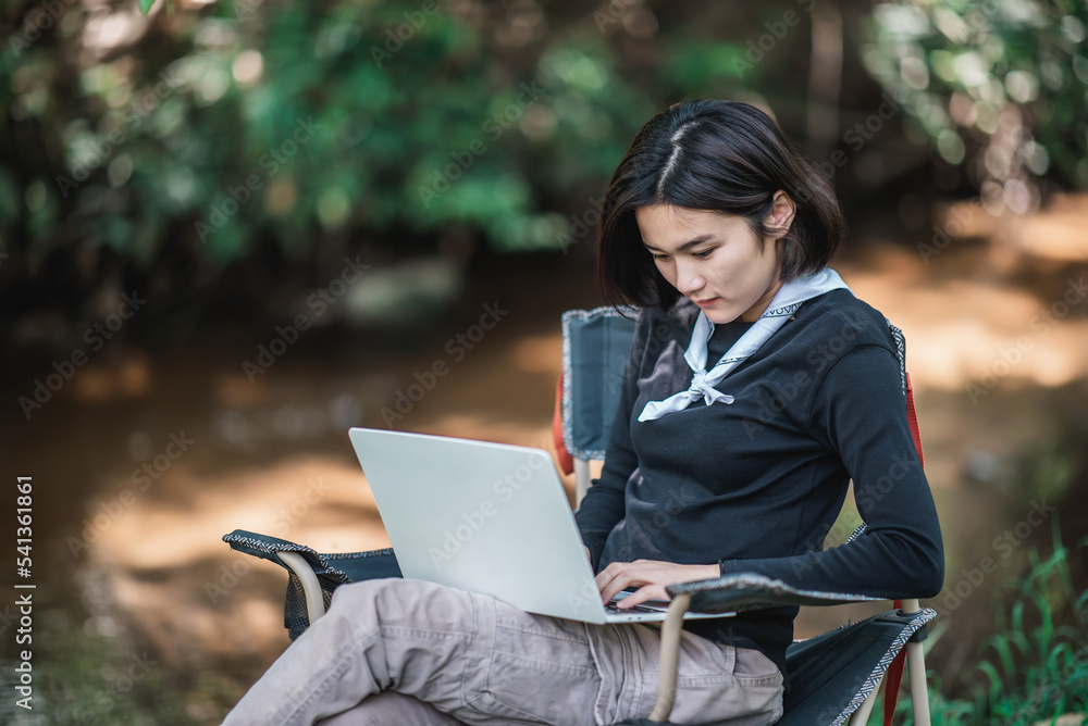 Young woman use laptop while camping in forest Young woman use laptop while camping in forest