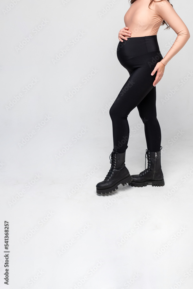 pregnant young woman posing in black leggings and a shirt on white background. comfortable clothes for Yoga and Fitness.practicing yoga at home. Prenatal breathing.motherhood and expectation concept pregnant young woman posing in black leggings and a shirt on white background. comfortable clothes for Yoga and Fitness.practicing yoga at home. Prenatal breathing.motherhood and expectation concept
