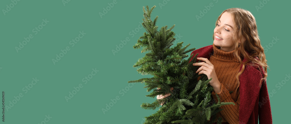 Pretty young woman with Christmas tree on green background with space for text