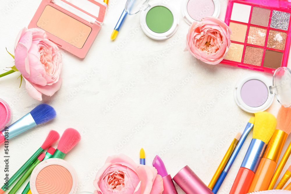 Frame made of decorative cosmetics, brushes and flowers on light background Frame made of decorative cosmetics, brushes and flowers on light background
