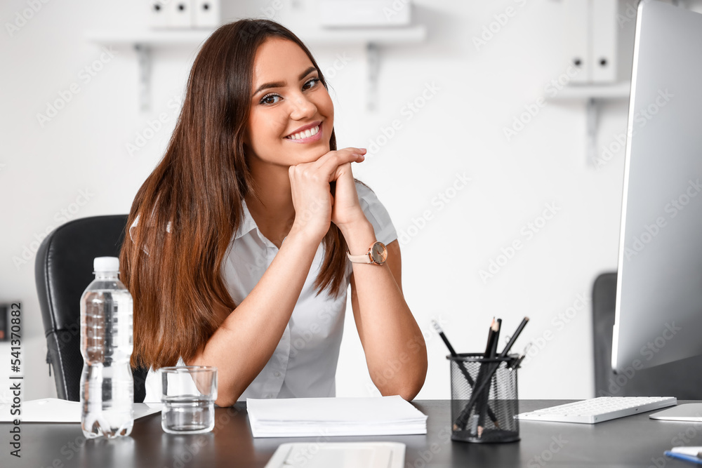 Smiling businesswoman sitting at table in office Smiling businesswoman sitting at table in office