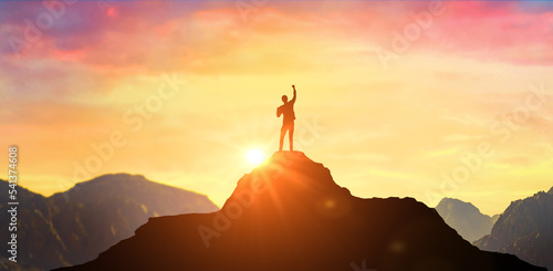 Success Business Leadership, Winner on top. Silhouette of businessman on top mountain, sky and sun light background. Business success and goal concept.