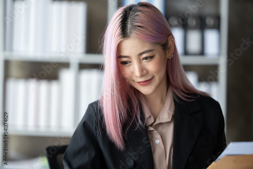 Upper body portrait of smiling young woman working in modern office with laptop computer at desk