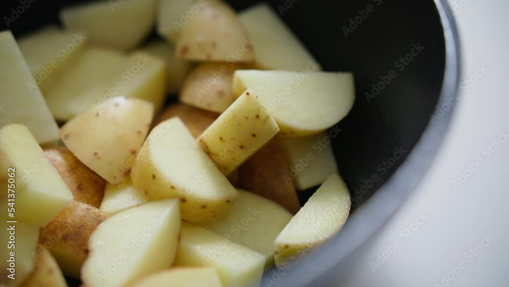 Chopped potatoes being thrown into a pan.