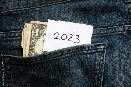One dollar lies in the pocket of jeans and a piece of paper with the inscription 2023, income