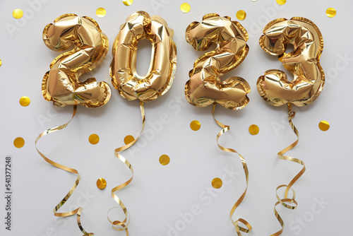 Figure 2023 made of balloons, confetti and serpentine on grey background