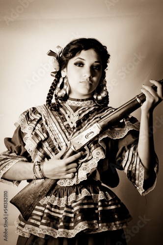 Retrato de una mujer modelo adolescente vistiendo un traje típico de Adelita de la Revolución Mexicana y sosteniendo un rifle photo