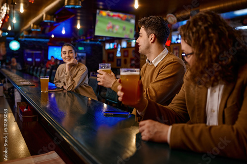 Canvas Print Young male friends flirting with woman at bar counter