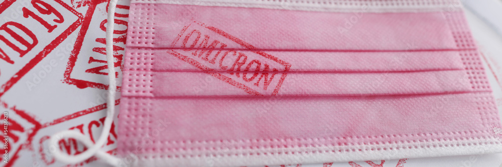 Pink face mask with omicron variant text on it, new omicron variant of coronavirus disease Pink face mask with omicron variant text on it, new omicron variant of coronavirus disease