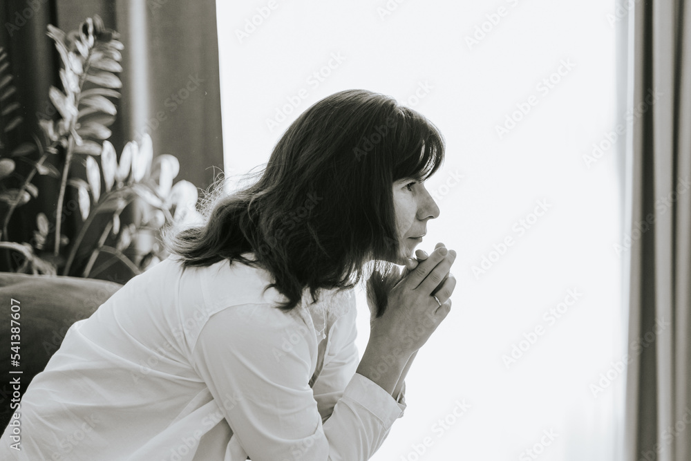 middle-aged woman is sitting on a sofa in a room and is sad, mental health, stress and hypochondria, worries and anxiety, black and white photo middle-aged woman is sitting on a sofa in a room and is sad, mental health, stress and hypochondria, worries and anxiety, black and white photo