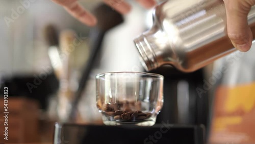 man pouring coffee beans to small cup to scale them before grind, coffee brewing process