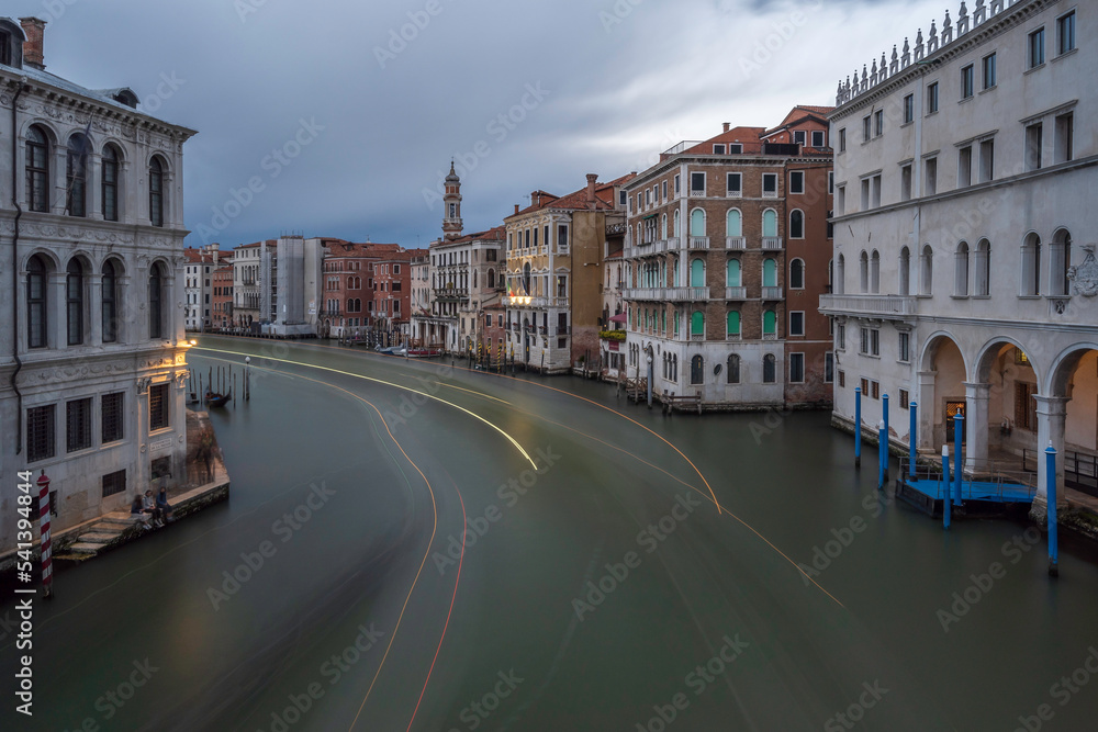 View from the Rialto Bridge with facades of picturesque old buildings on the Grand Canal, gondolas and boats in Venice.