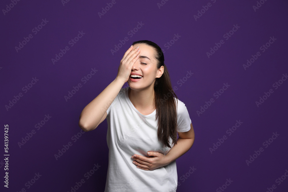 Beautiful young woman laughing on purple background. Funny joke Beautiful young woman laughing on purple background. Funny joke