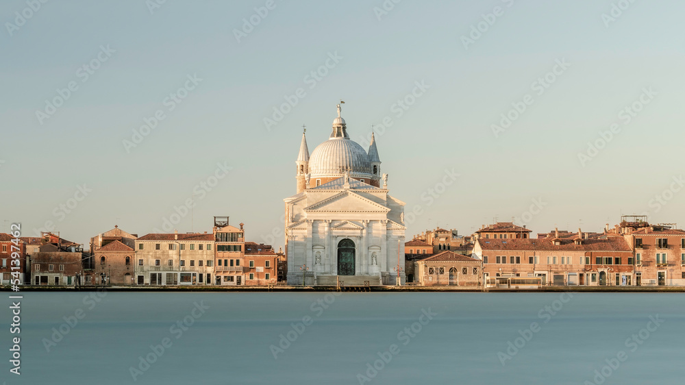 Chiesa del Santissimo Redentore catholic church and row of buildings on fondamenta embankment of Giudecca island canal in Venetian Lagoon, at sunrise, from Venice city, Veneto region, Northern Italy