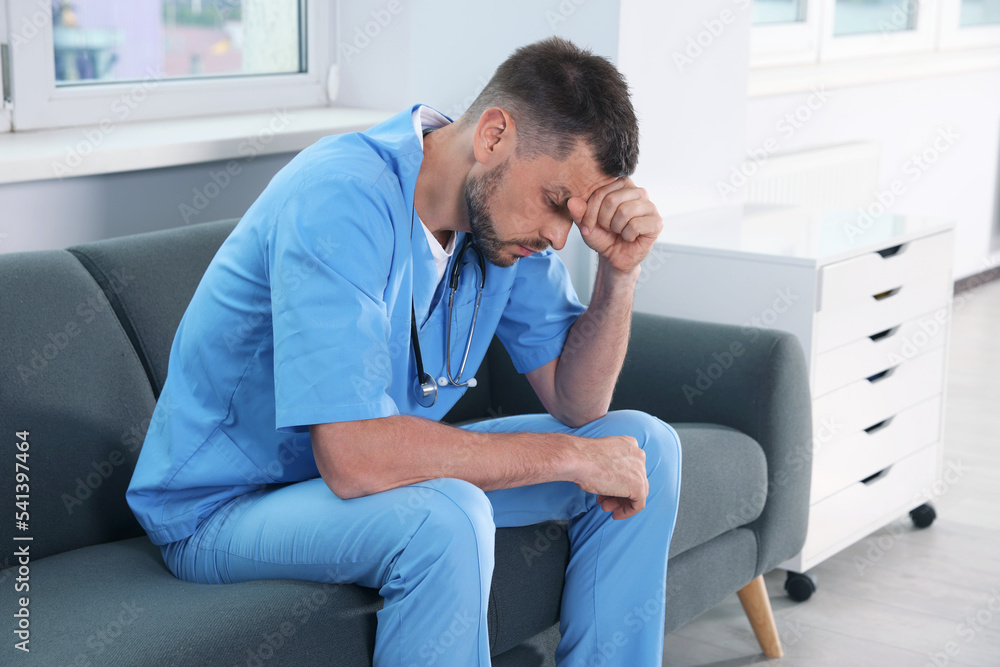 Exhausted doctor sitting on sofa in hospital