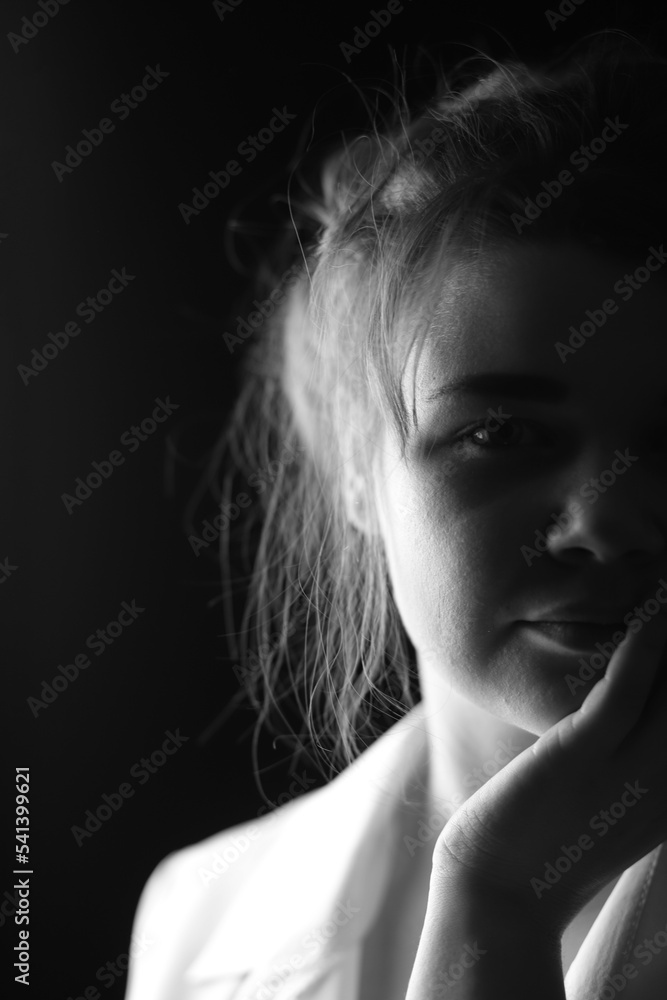 Black and white portrait of an attractive girl on a black studio background. Vertical Orientation