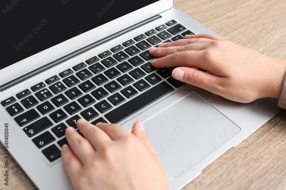 Woman working on laptop at wooden table, closeup Woman working on laptop at wooden table, closeup