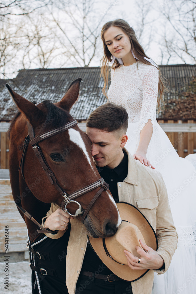 Obraz premium Couple in love riding horses on ranch at sunset in winter.