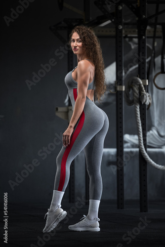 Sports girl in a grey jumpsuit in the gym. Sport photoshoot