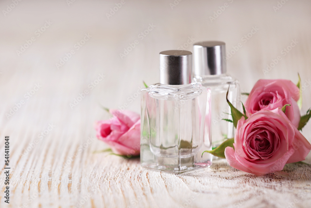 Bottles of essential oils and roses on white wooden table, space for text Bottles of essential oils and roses on white wooden table, space for text
