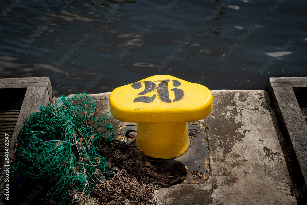 The yellow shoreside bitts. The posts are used to secure mooring lines