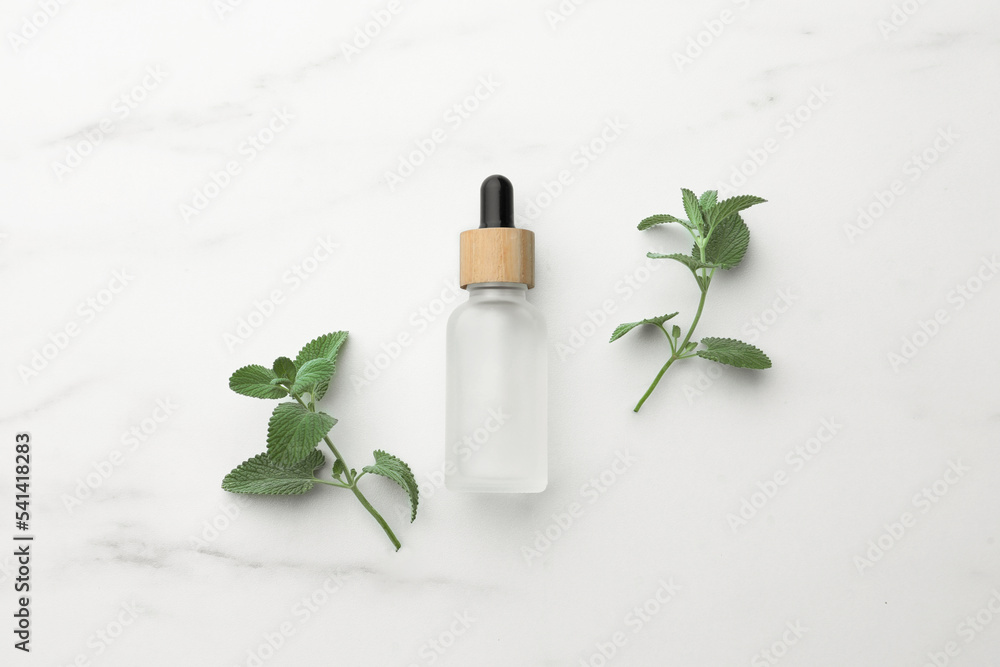 Bottle of mint essential oil and fresh herb on white marble table, flat lay Bottle of mint essential oil and fresh herb on white marble table, flat lay