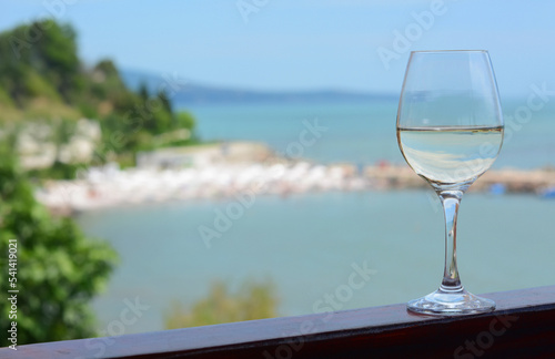Glass with wine on railing near sea. Space for text