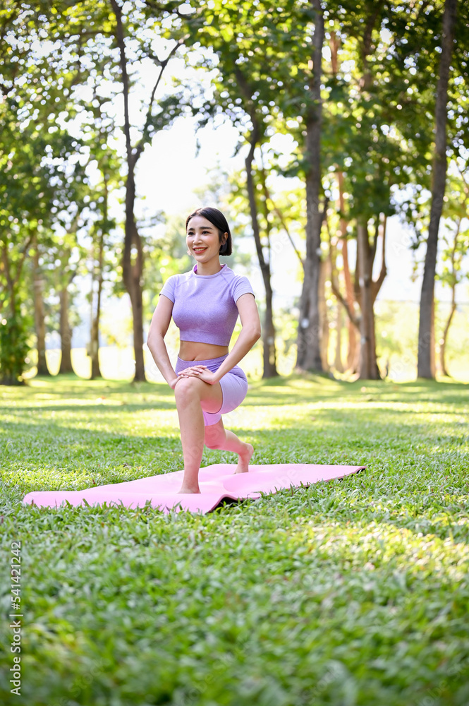 Beautiful healthy Asian woman practicing yoga in park. Healthy lifestyle concept