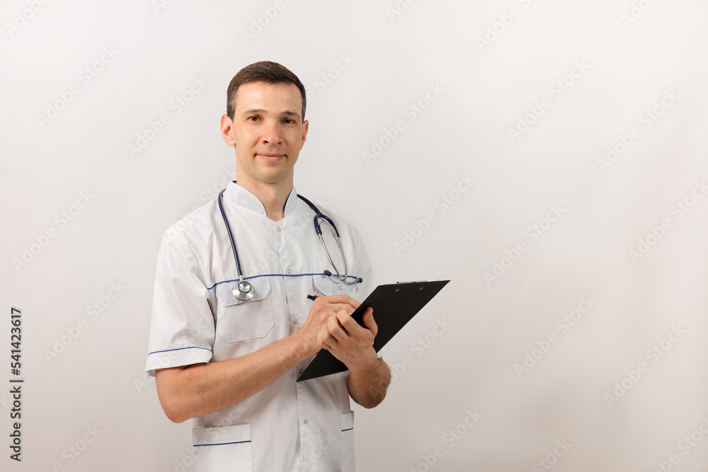 Medical services. Young doctor with stethoscope and clipboard looking at camera. Copy space. Medical services. Young doctor with stethoscope and clipboard looking at camera. Copy space.