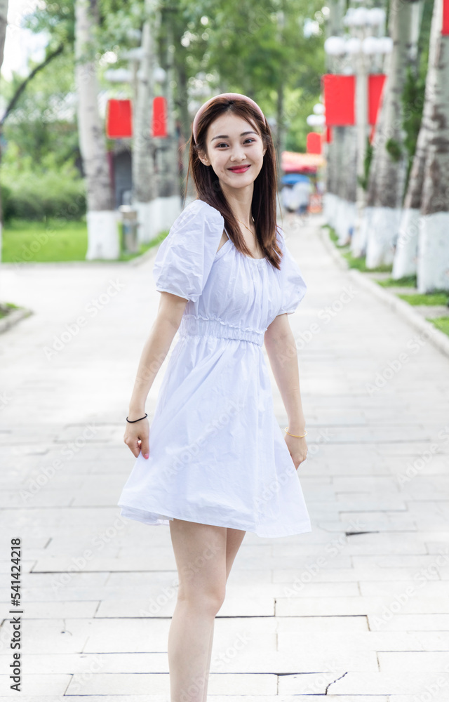 An Asian girl in a white dress playing in the park