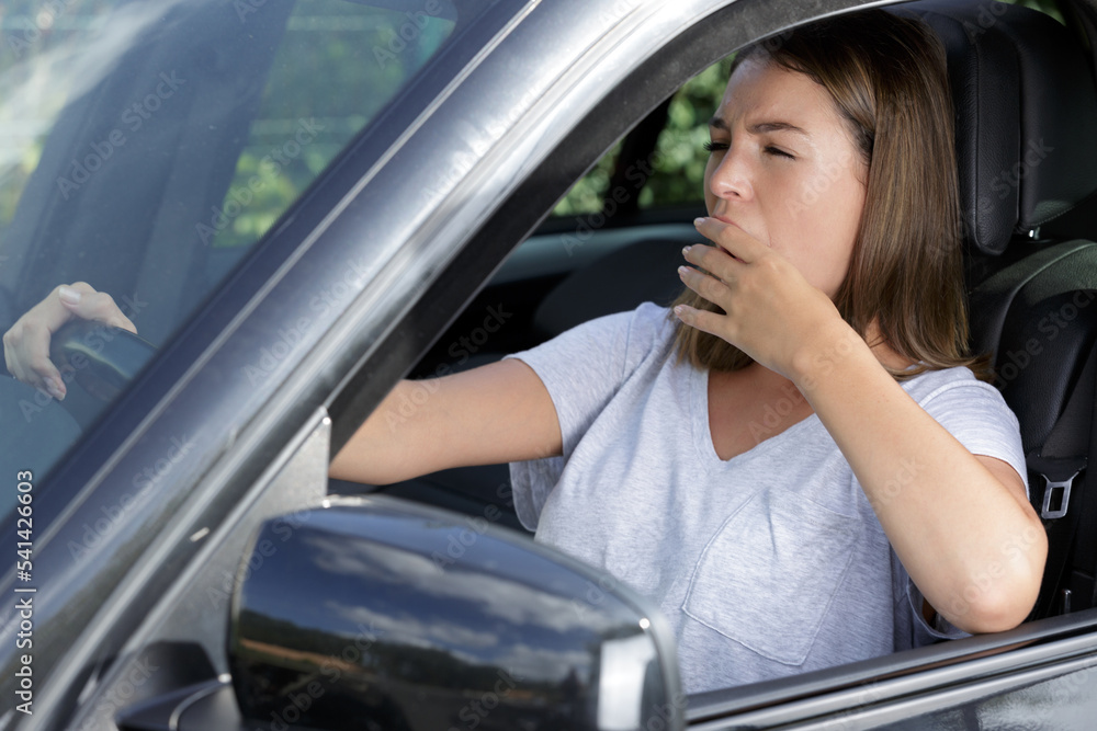 a woman yawning while driving a woman yawning while driving