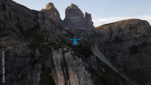 Drone shot of a hiker standing on a top of rocky hill on a sunny day photo