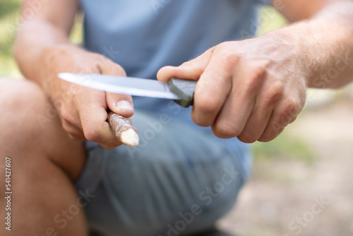 young man with a knife cut a wooden stick © auremar