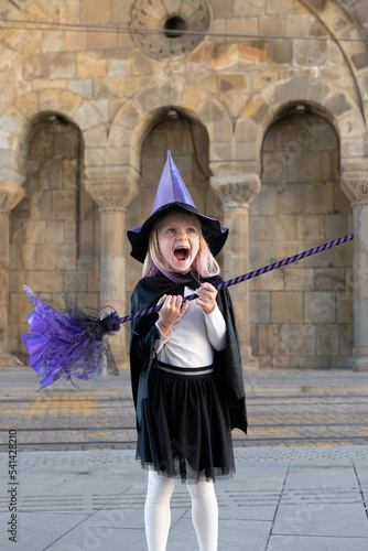 blonde girl in halloween costume violet wich hat and broom