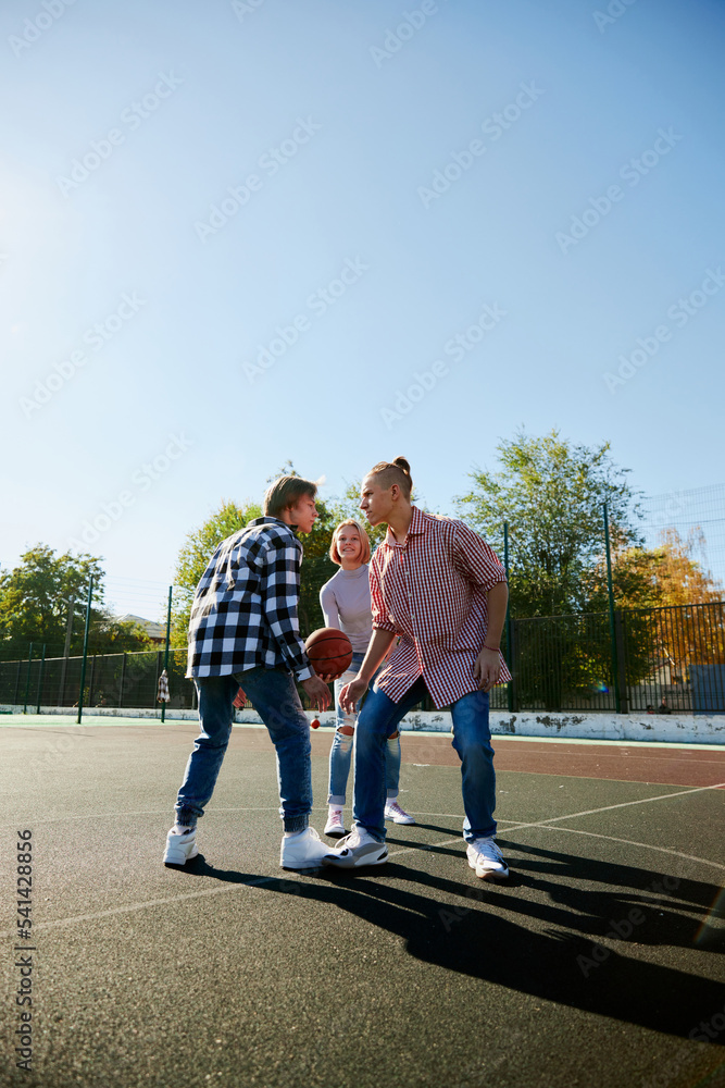 Group of friends bonding outdoors to play street basketball. Teens wearing casual style clothes. Kids look happy, delighted. Sport, energy, motion Group of friends bonding outdoors to play street basketball. Teens wearing casual style clothes. Kids look happy, delighted. Sport, energy, motion