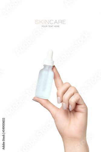Beautiful groomed woman's hand holding up opaque dropper bottle in skincare concept