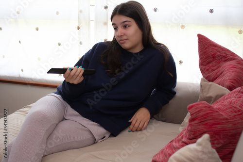 Joven adolescente femenina aburrida viendo la tele mientras cambia de canal