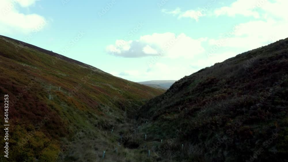 travelling drone shot of a lush green valley with a stream running down the middle with a very old rock formation at the bottom. travelling drone shot of a lush green valley with a stream running down the middle with a very old rock formation at the bottom.