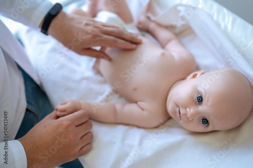 Male pediatrician examining a baby and looking involved