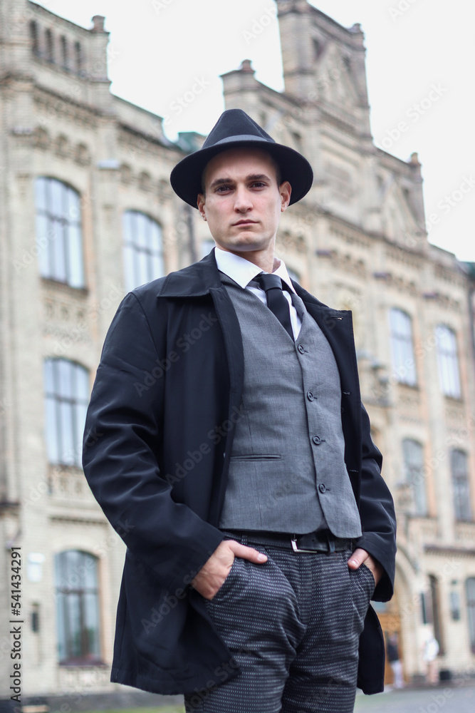 Men's photo shoot in a classic plaid suit and a hat against the backdrop of an old building. Men's photo shoot in a classic plaid suit and a hat against the backdrop of an old building.