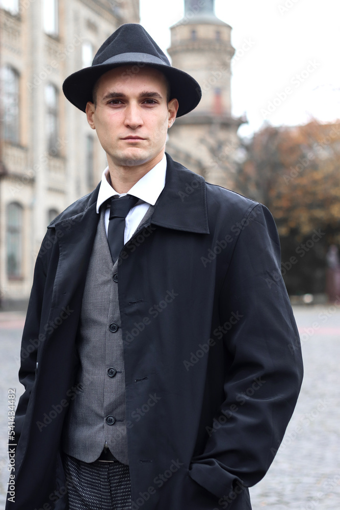 Men's photo shoot in a classic plaid suit and a hat against the backdrop of an old building. Men's photo shoot in a classic plaid suit and a hat against the backdrop of an old building.