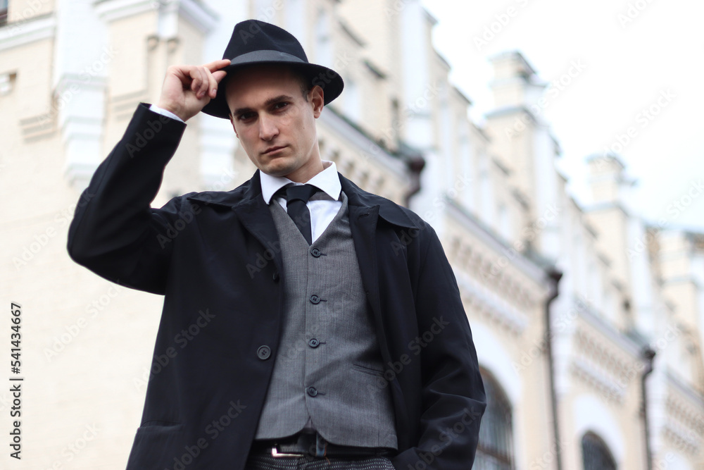 Men's photo shoot in a classic plaid suit and a hat against the backdrop of an old building. Men's photo shoot in a classic plaid suit and a hat against the backdrop of an old building.