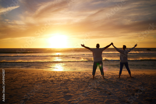 Love, sunset and couple on beach for freedom, peace and calm for happiness, relax and carefree outdoor together. Romance, man and woman stand on holiday, vacation and travel holding hands to worship