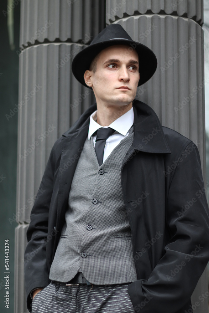 Men's photo session in a classic checkered suit and hat against the backdrop of columns. Men's photo session in a classic checkered suit and hat against the backdrop of columns.