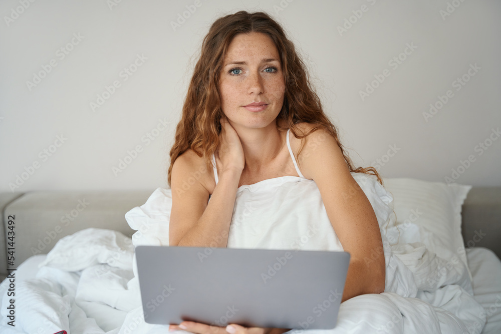 Woman sits in bed in nightgown and works with gadget Woman sits in bed in nightgown and works with gadget
